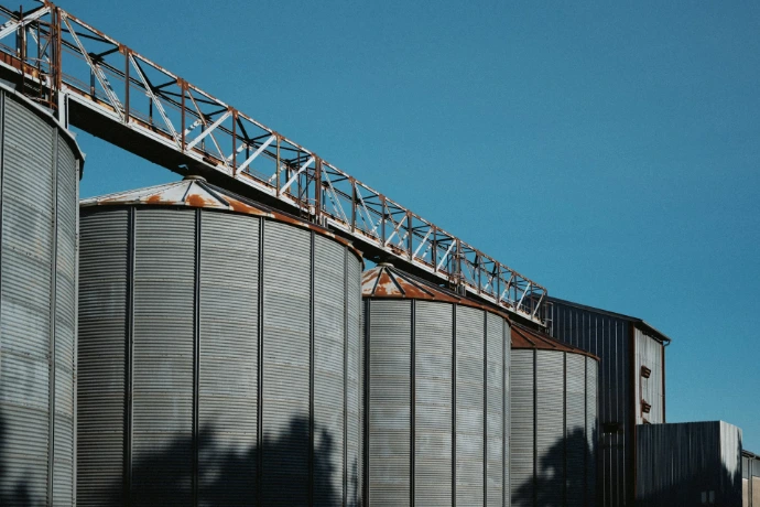 Grain silos stand beneath a blue sky.